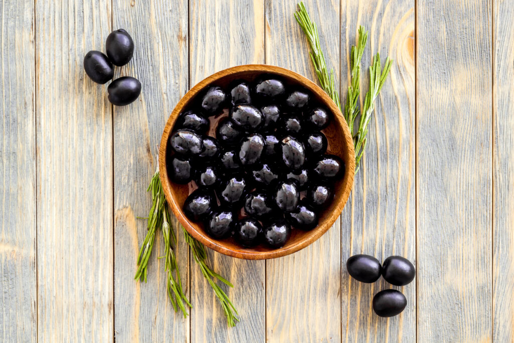 Wooden bowl of pickled black olives, top view